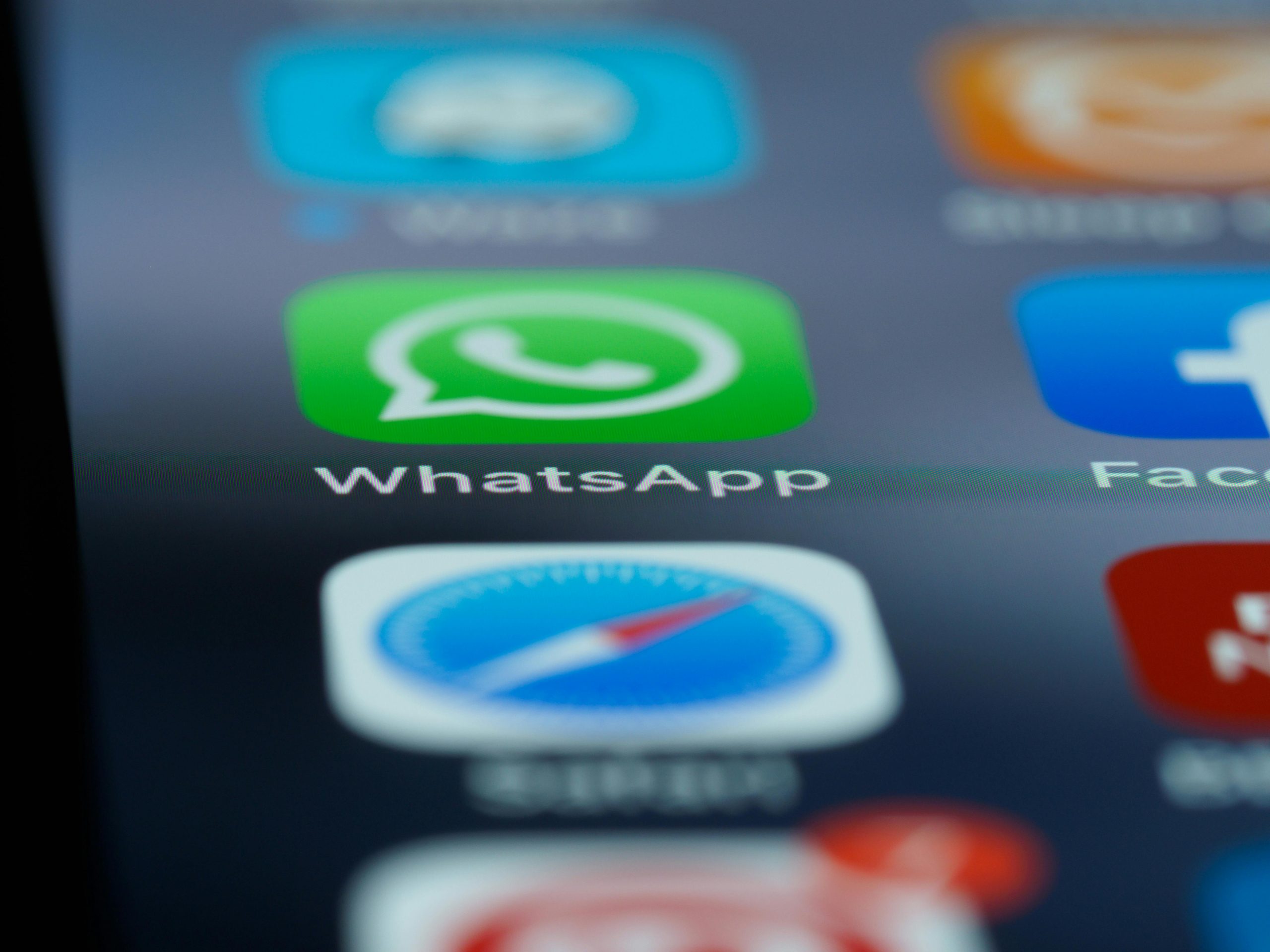 Detailed close-up of a smartphone's home screen displaying popular applications like WhatsApp.